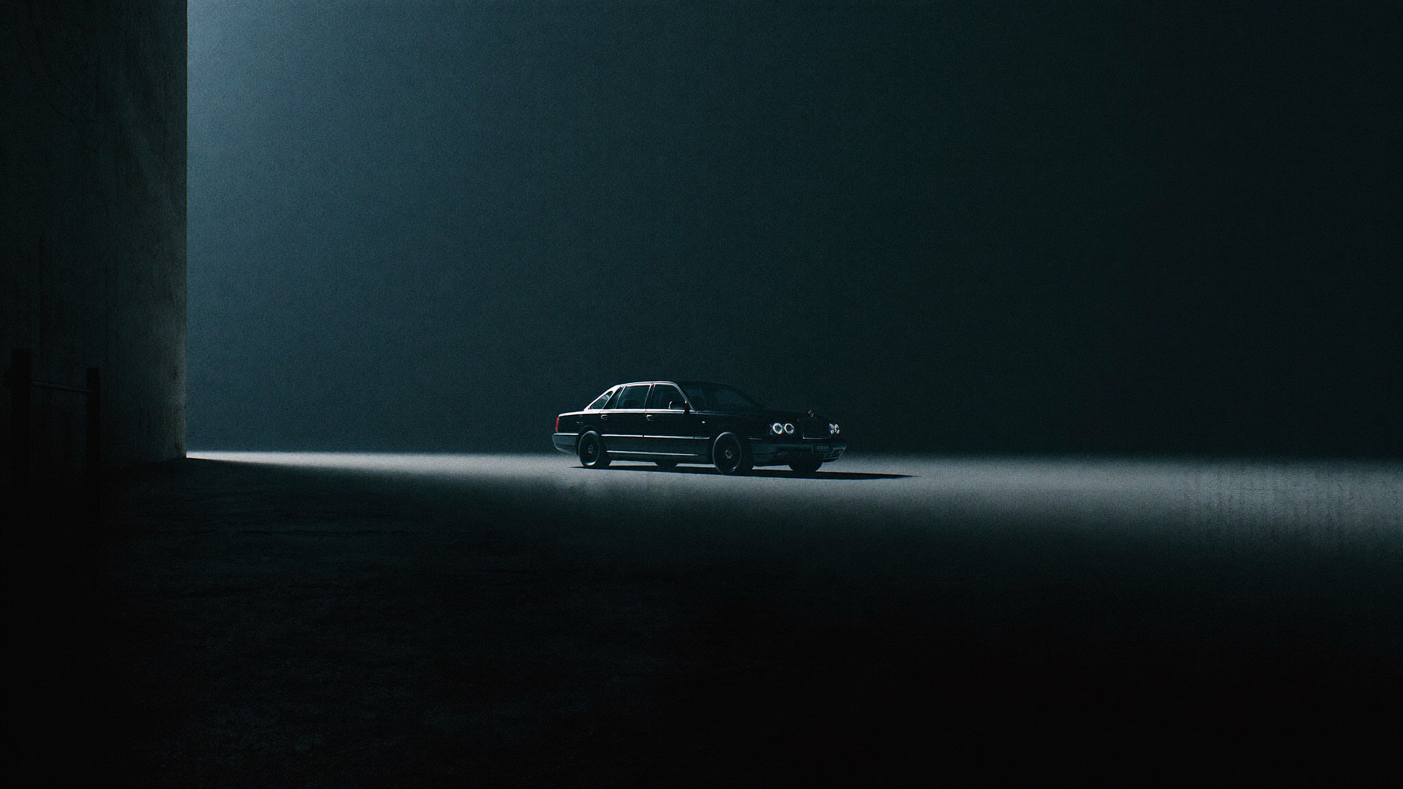 Wide cinematic view of a black luxury car in a vast dark architectural space